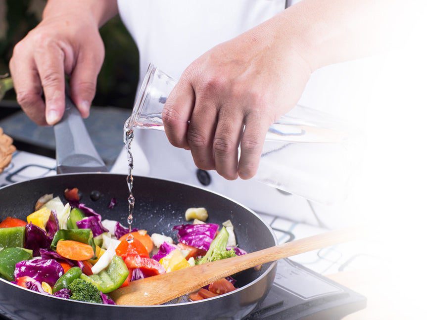 Chef pouring water into a stir fry