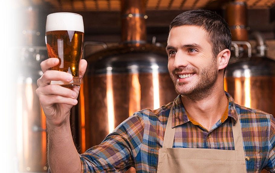 Brewer holding up a fresh brewed beer for the taste testing